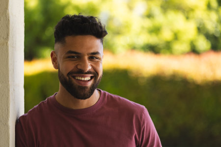 Smiling man outdoors enjoying sunny day, leaning against wall, feeling relaxed. Relaxation, happiness, sunshine, leisure, lifestyle, peacefulの写真素材