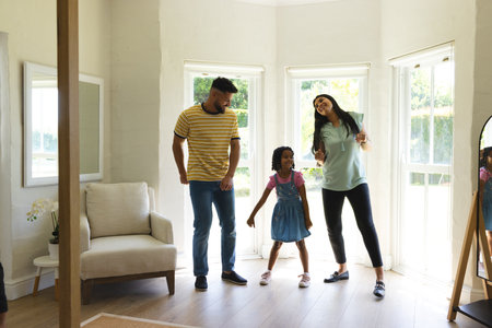 Family dancing together in living room, enjoying quality time and laughter. togetherness, happiness, bonding, joyful, celebration, musicの写真素材