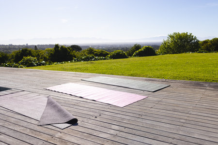 Yoga mats on wooden deck overlooking scenic landscape, ready for outdoor exercise, copy space....