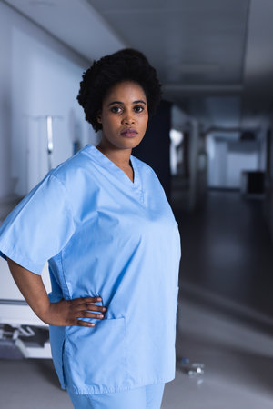 African American nurse in scrubs standing confidently in hospital corridor. Healthcare, professional, medical, confidence, hospital staff, wellnessの写真素材