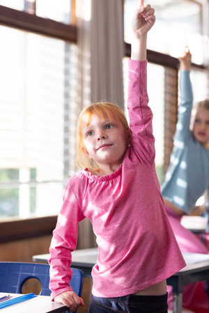 In school, girl raising hand in classroom, eager to answer question. Education, learning, studying,...