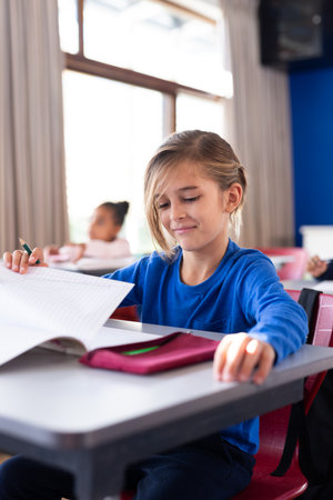 In school, boy opening notebook and preparing for class at desk. education, back to school, learning, studying, childhood, preparationの写真素材