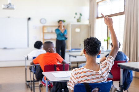 In school, student raising hand to ask question in classroom with Indian female teacher. Education, learning, participationの写真素材