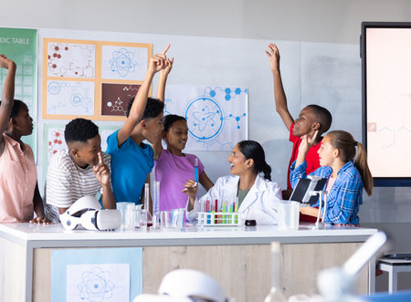 In school, students raising hands and engaging with Indian female teacher in science classroom. Education, learning, engagementの写真素材