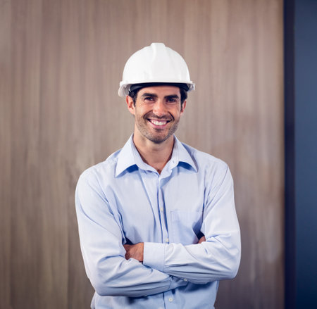 Portrait of two architects standing with arms crossed in office and colleagues working in background