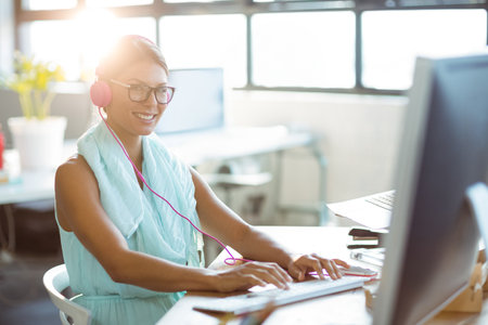 Portrait of smiling business executive listening to music while working on computer