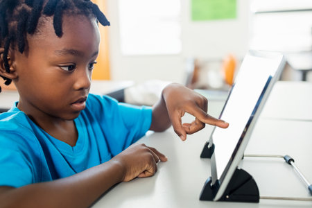 Side view of pupil using tablet pc in classroom at elementary school