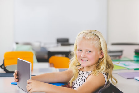 Portrait of schoolgirl using digital tablet in classroom at school