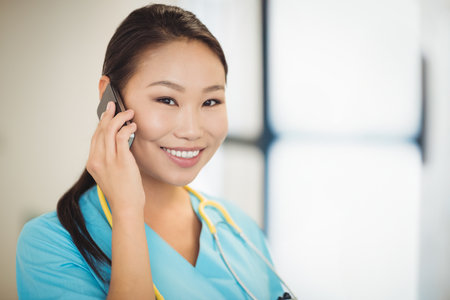 Portrait of nurse talking on mobile phone in hospitalの写真素材