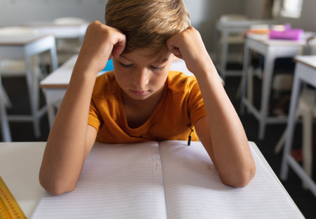 Schoolboy sitting at desk in classroom, focusing on open notebook and yellow ruler. Student,...
