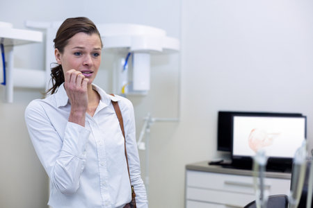 Woman suffering from toothache while dentist checking her report at dental clinicの写真素材