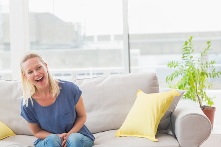 Surprise mother looking at girl hiding bouquet behind back at homeの写真素材