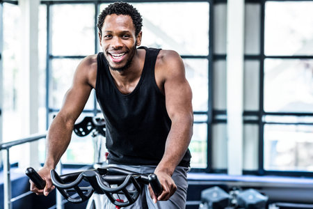 Fit man working out at spinning class in the gymの写真素材
