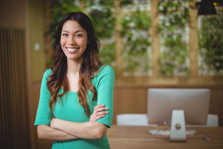 Female executive standing with arms crossed in officeの写真素材