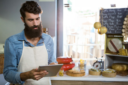 Attentive staff using digital tablet at counter in market
