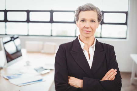 Portrait of confident businesswoman with colleague working in background at officeの写真素材