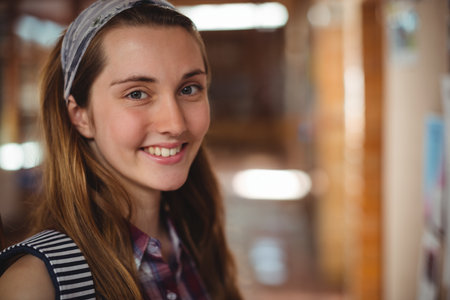 Portrait of smiling schoolgirl standing near notice board in corridor at schoolの写真素材