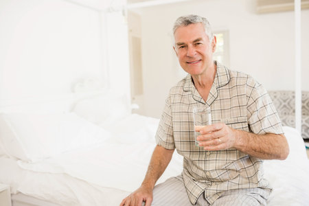 Peaceful senior man holding glass of water at homeの写真素材