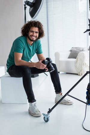 Portrait of smiling photographer sitting in the studio with the camera
