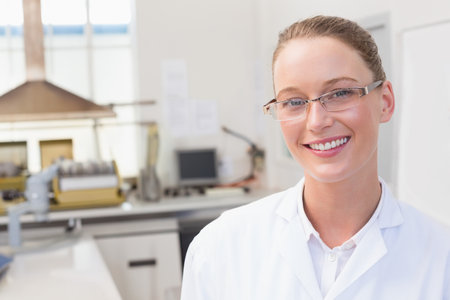 Female lab technician wearing white lab coat analyzing sample at bench with fume hood, copy space. Scientist, research, innovation, technology, precision, healthcare, cleanlinessの写真素材