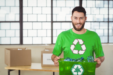 Man standing holding green recycling bin with bottles in community center sorting area, copy space. Environmentalism, sustainability, eco-friendly, volunteer, conservation, donation, cleanlinessの写真素材