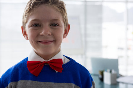 School-age boy standing close to camera in office area, wearing bow tie near whiteboard, copy space. Adolescence, educational, professional, innovative, formal, focused, bright