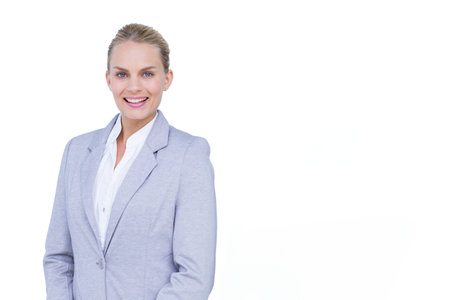 Woman smiling and standing facing camera in studio wearing gray blazer and white blouse, copy space. Professional, corporate, clean, minimalist, confident, polished, executiveの写真素材