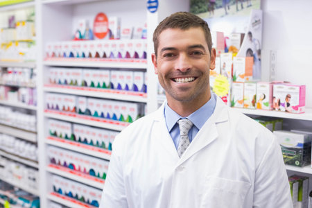 Male pharmacist standing in pharmacy aisle with medicine boxes wearing coat and tie, copy space. Healthcare, professionalism, medical, retail, organization, trust, wellnessの写真素材