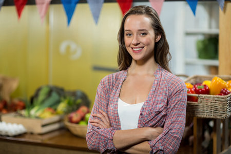 Female vendor arranging baskets of bell peppers and apples at market stall under bunting flags. Fresh produce, marketplace, rustic, vibrant, healthy living, retail environment, organicの写真素材