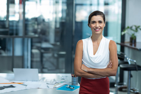Woman in business attire standing at office desk arranging documents, pens and laptop, copy space....