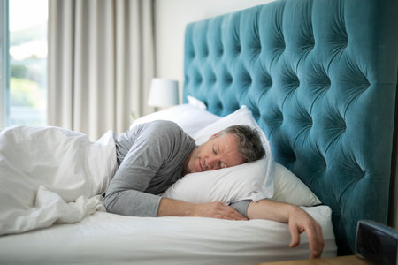 Mature man sleeping on side in master bedroom on white pillow under duvet, copy space. Serenity, relaxation, cozy, tranquil, home, interior, comfort