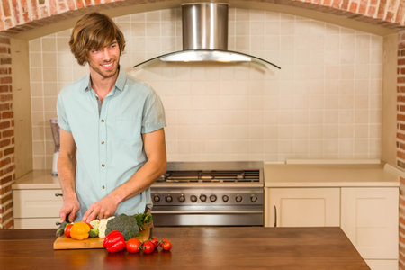 Man wearing green shirt chopping peppers broccoli cauliflower on kitchen countertop, copy space. Cooking, culinary, home, domestic, rustic, preparation, healthyの写真素材