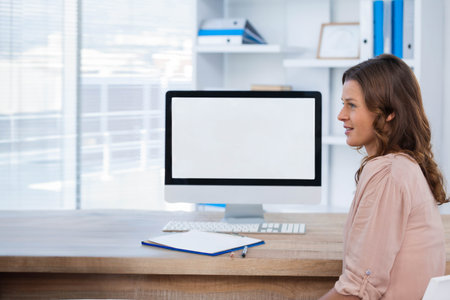 Female office professional typing on computer keyboard at office desk with clipboard, copy space. Businesswoman, workspace, minimalism, corporate, productivity, professional, office environmentの写真素材