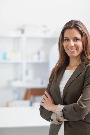 Woman crossing arms while smiling in modern lab with white shelving unit behind, copy space. Professional, minimalist, wellness, confident, modern, workspaceの写真素材