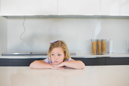 Female child leaning on quartz counter in kitchen, viewing cereal canisters beside stovetop cable. Youth, kitchen, minimalism, interior, home, lifestyleの写真素材