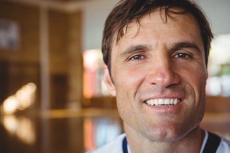 Middle-aged man smiling at camera in wood-paneled studio wearing white shirt with navy collar.の写真素材