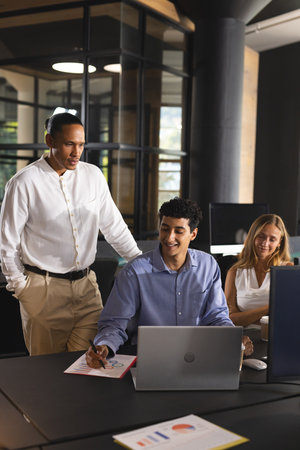 Collaborating in modern office, business professionals discussing project details on laptop....