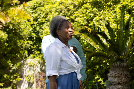 African American woman enjoying sunny day in garden, smiling and looking content.の写真素材