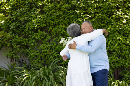 Senior couple embracing warmly in garden, surrounded by lush greenery. Togetherness, retirement, affection, companionship, outdoors, countrysideの写真素材