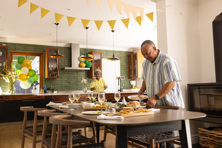 Senior couple preparing festive table in kitchen, enjoying celebration together. family, gathering, preparation, holiday, tradition, elderlyの写真素材