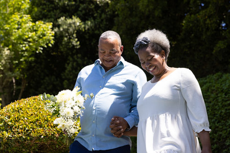 African American senior couple walking hand in hand outdoors, smiling joyfully. Elderly, happiness, retirement, companionship, togetherness, lifestyleの写真素材