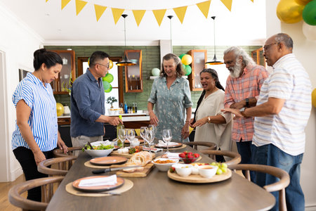 Gathering around dining table, senior friends preparing meal and having conversation. Friendship, food, kitchen, cooking, bonding, dinner