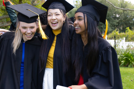Graduating students in caps and gowns celebrating together outdoors, smiling happily. Graduation, achievement, university, celebration, success, educationの写真素材