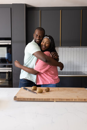 African American couple hugging in modern kitchen, smiling with joy and happiness. joyful, affection, family, lifestyle, love, togethernessの写真素材