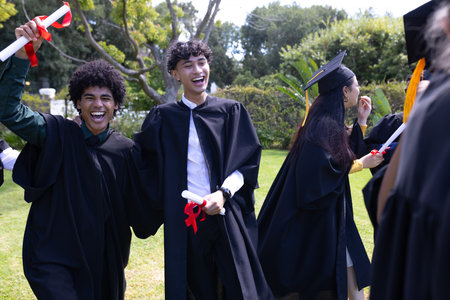 Celebrating outdoors, graduating students holding diplomas and smiling joyfully. Graduation, achievement, celebration, accomplishment, educationの写真素材