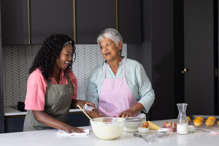 Baking together in kitchen, African American women sharing joyful moments and laughter. Cooking, friendship, happiness, culinary, lifestyle, domesticの写真素材