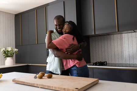 African American couple embracing in modern kitchen, expressing joy and affection. love, relationship, happiness, home, lifestyleの写真素材