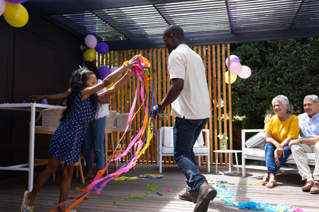 Celebrating outdoors, family dancing with colorful streamers, sharing joyful moments together. celebration, togetherness, happinessの写真素材