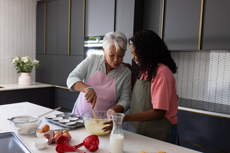Baking together in kitchen, grandmother and granddaughter sharing joyful moment. Family, bonding,...