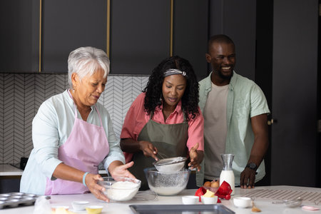 Baking together in kitchen, three generations sharing laughter and preparing ingredients. Family, bonding, cooking, multigenerational, home, traditionの写真素材